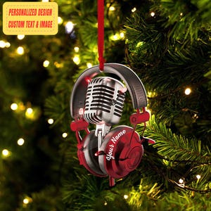 May include: A festive Christmas tree ornament featuring a silver microphone and red headphones. The ornament is suspended by a red ribbon. The ear cup of the headphones has the text "Your Name" and a yellow tag reads "Personalized Design Custom Text & Image".