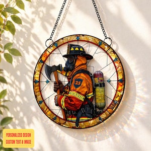 Puede incluir: Ventana redonda de vidrieras con un bombero con uniforme naranja, sosteniendo un hacha. El diseño incluye el texto "DAVID" y "25" en el uniforme. La ventana está suspendida por una cadena negra. Las palabras "PERSONALIZED DESIGN CUSTOM TEXT & IMAGE" están en un cuadro amarillo.