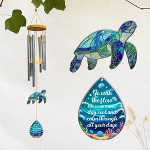 Puede incluir: Una colección de decoraciones con temática oceánica, que incluye una carillón de viento con tubos plateados y una parte superior de madera, una tortuga marina de estilo vidriera y un letrero en forma de lágrima. El letrero dice "Go with the flow, like ocean waves, stay cool and calm through all your days."