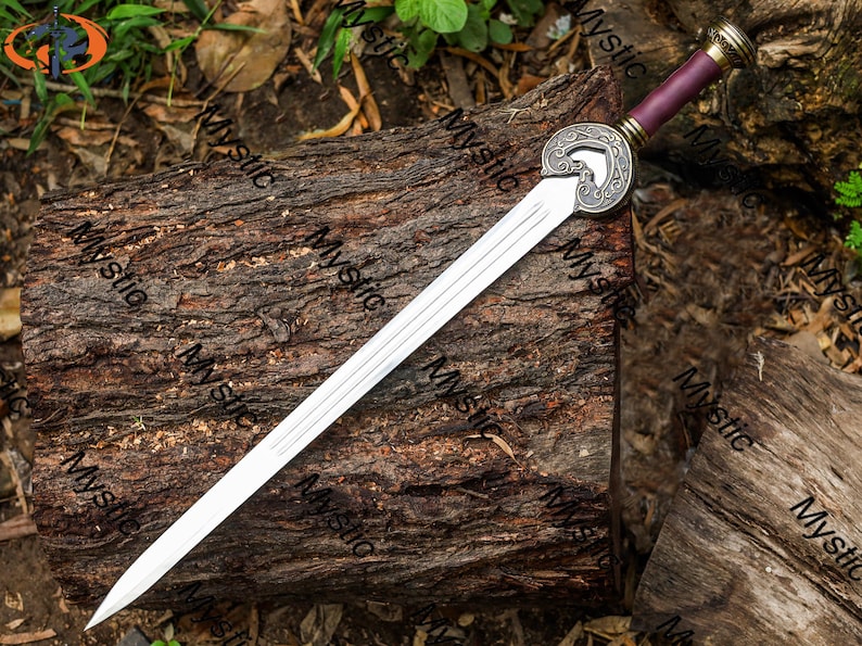 Puede incluir: Una espada plateada con una empu&ntilde;adura decorativa y un mango morado descansa sobre un tronco de madera desgastado. La espada presenta un dise&ntilde;o circular detallado cerca de la base de la hoja y un borde afilado pulido. El mango tiene detalles dorados.