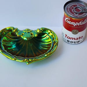 Peut inclure: Un plat en forme de coquillage avec une finition iris&eacute;e verte et dor&eacute;e, dot&eacute; d'un bord festonn&eacute; et d'un motif d&eacute;coratif central. &Agrave; c&ocirc;t&eacute; du plat se trouve une bo&icirc;te de soupe &agrave; la tomate Campbell's de 305g pour montrer l'&eacute;chelle de taille.