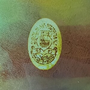 Peut inclure: Un autocollant de forme ovale avec un fond cr&egrave;me et du texte brun appliqu&eacute; sur une surface translucide et iris&eacute;e. L'autocollant pr&eacute;sente un graphique central, le texte "1983", "ECS" et "HAND-PAINTED" imprim&eacute; en police brune lisible.