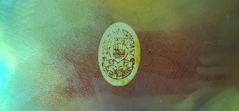 Peut inclure: Un autocollant de forme ovale avec un fond cr&egrave;me et du texte brun appliqu&eacute; sur une surface translucide et iris&eacute;e. L'autocollant pr&eacute;sente un graphique central, le texte "1983", "ECS" et "HAND-PAINTED" imprim&eacute; en police brune lisible.