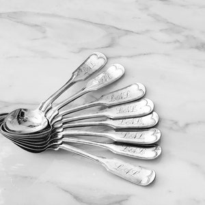 May include: A set of ten silver spoons with ornate handles. Each spoon is engraved with the word "LOVE".