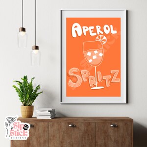 May include: Orange and white printable art print with the text "Aperol Spritz" and a glass of Aperol Spritz with an orange slice.
