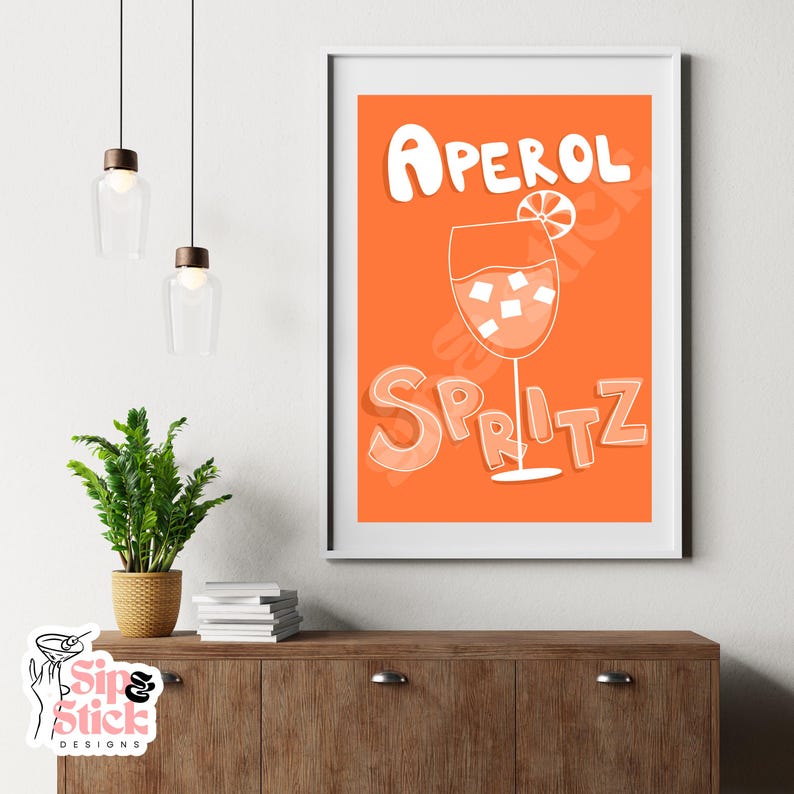 May include: Orange and white printable art print with the text "Aperol Spritz" and a glass of Aperol Spritz with an orange slice.