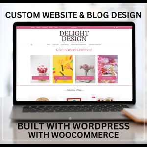 Peut inclure: Un ordinateur portable affichant un site web pour une entreprise de fournitures artisanales et de fête appelée "Delight Design". Le site web présente une palette de couleurs rose et blanche et une bannière qui dit "Craft! Create! Celebrate!" Le site web comprend également une section pour la Saint-Valentin.