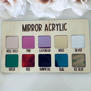 May include: A wooden display board with the text "MIRROR ACRYLIC" and samples of various colored mirror acrylics. Colors include rose gold, pink, lavender, gold, silver, green, red, gunmetal, teal, and ice blue.