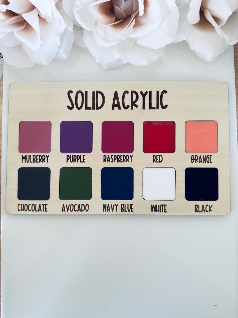 May include: A wooden color chart labeled "SOLID ACRYLIC" with ten color swatches: Mulberry, Purple, Raspberry, Red, Orange, Chocolate, Avocado, Navy Blue, White, and Black. The colors are displayed in square shapes.