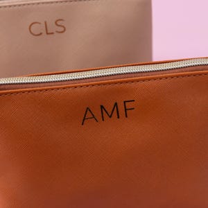 May include: Two zippered pouches, one brown and one beige, with personalized initials. The brown pouch has the initials "AMF" and the beige pouch has the initials "CLS".