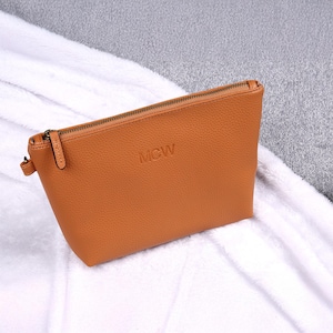 May include: A tan leather zippered pouch with the initials "MCW" embossed on the front.