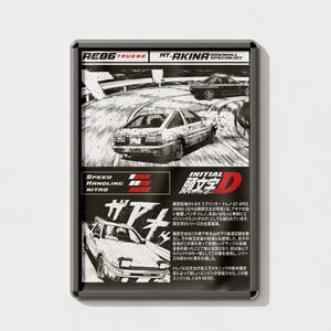 May include: A black and white illustration of a Toyota Sprinter Trueno AE86, a popular car from the Initial D anime series. The car is shown driving on a winding mountain road. The text "AE86 TRUEND MT-AKINA DOWNHILL SPECIALIST" is at the top of the image. The text "SPEED HANDLING NITRO" is in the lower left corner of the image. The text "INITIAL D 頭文字D" is in the lower right corner of the image.