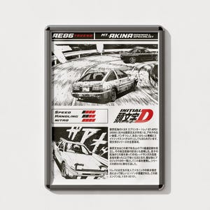 Può includere: Un magnete rettangolare con un'illustrazione in bianco e nero in stile manga di un'auto Toyota AE86 Trueno in corsa. Il magnete include testo giapponese e le parole "SPEED", "HANDLING" e "NITRO".