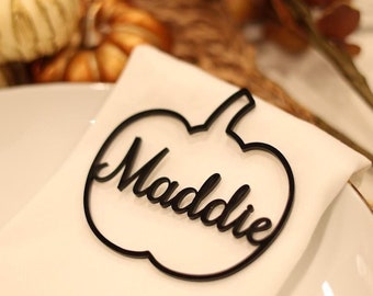 Puede incluir: Tarjeta de lugar de calabaza negra con el nombre Maddie escrito en cursiva.