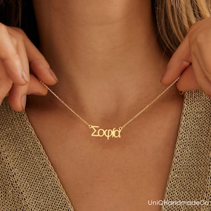 May include: A gold necklace with the name "Sophia" spelled out in Greek letters.