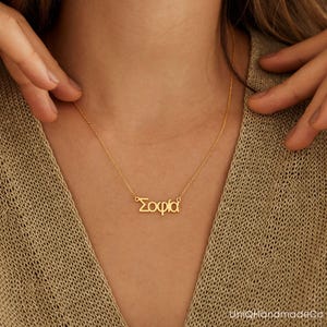 May include: A gold necklace with the name "Sophia" spelled in Greek letters.