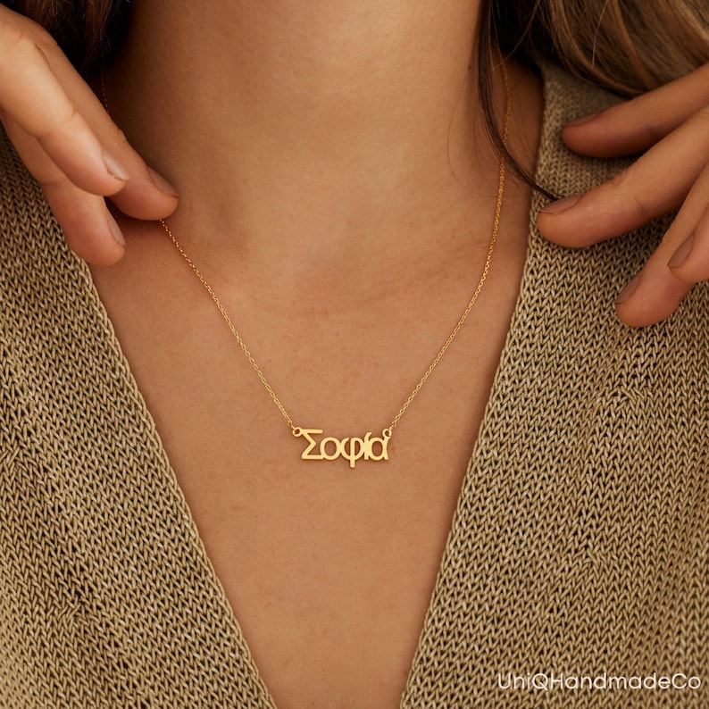 May include: A gold necklace with the name "Sophia" spelled in Greek letters.