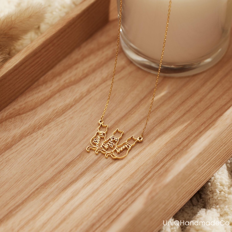 May include: Gold necklace featuring three cat silhouettes, each with a name inscribed: Maggie, Lily, and Luna.