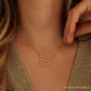 May include: Gold necklace featuring three cat silhouettes, each with a name inscribed inside: Maggie, Billy, and Lucy.