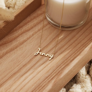 May include: A gold necklace with the name "Jenny" written in cursive script.