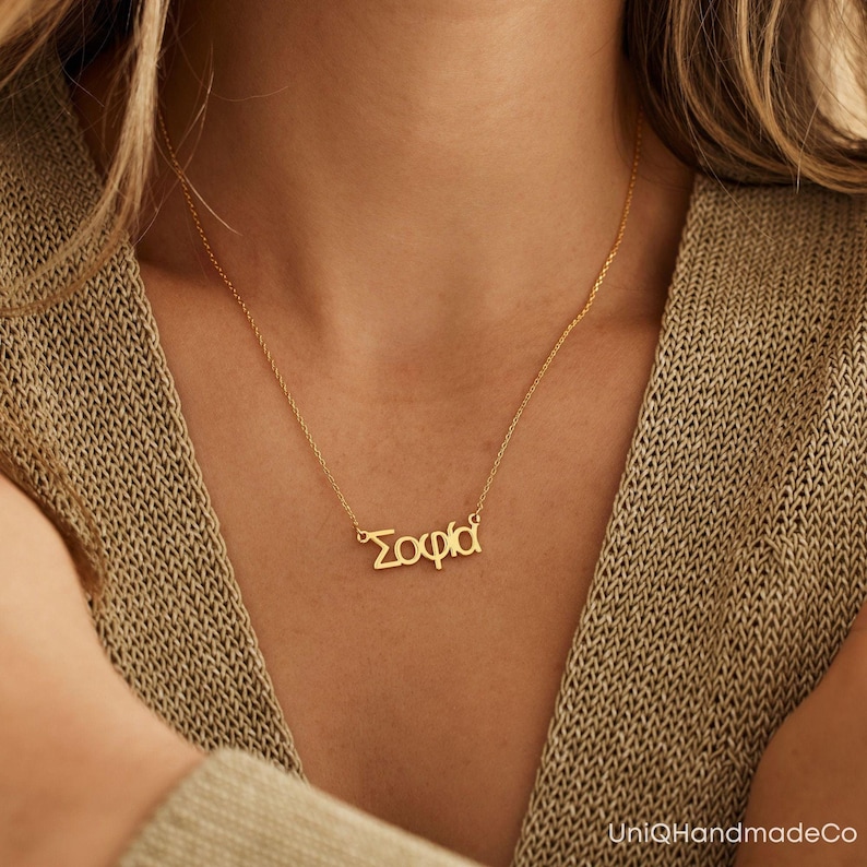 May include: A gold necklace with the name "Sophia" spelled in Greek letters.