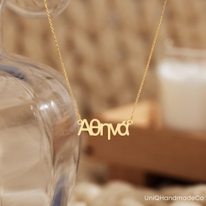 May include: A gold necklace with the name "Athena" spelled out in Greek letters.