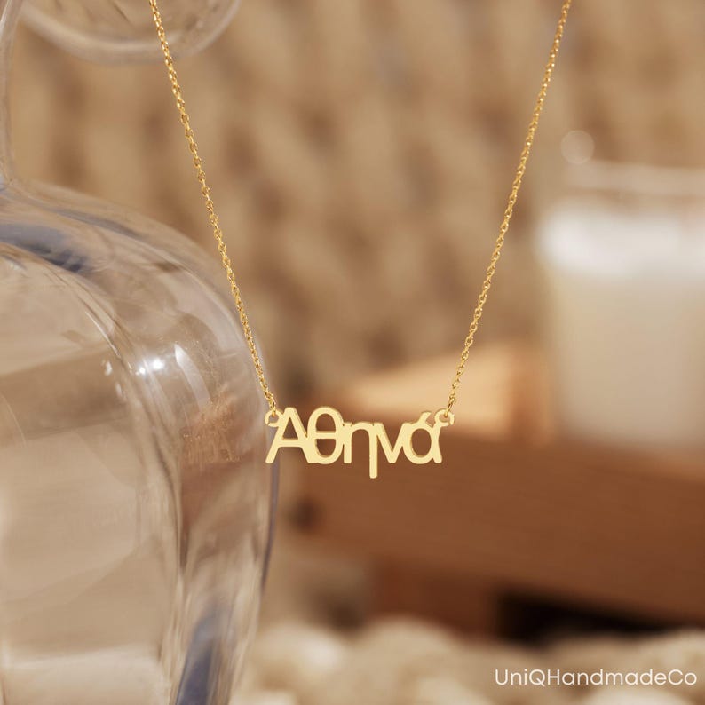 May include: A gold necklace with the name "Athena" spelled out in Greek letters.