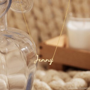 May include: A gold necklace with the name "Jenny" written in cursive script.