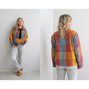 May include: A multi-colored plaid jacket with a button closure. The jacket is made of a woven fabric and has a relaxed fit.