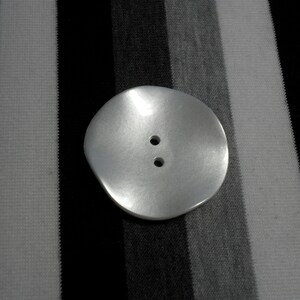 White, wavy, 2-hole resin button. 1 7/8&quot;