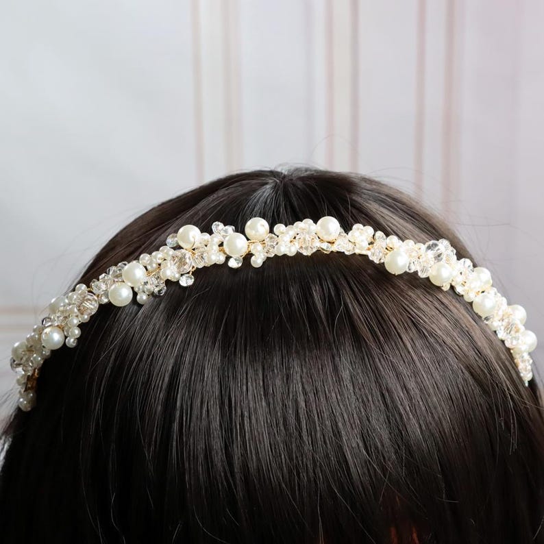 May include: A delicate bridal headband featuring faux pearls and clear crystals. The gold-toned wire base is adorned with clusters of ivory pearls and sparkling crystals, creating a romantic and elegant accessory for weddings or special occasions.