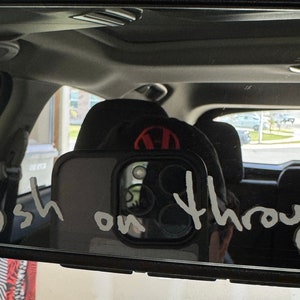 Pu&ograve; includere: Uno specchietto retrovisore in un'auto con le parole "Push on through" scritte sopra con un pennarello bianco.