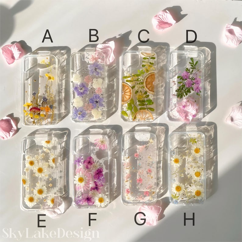 May include: Clear phone cases with embedded dried flowers and fruit. Designs include daisies, lavender, and orange slices. The cases are labeled A through H. The SkyLakeDesign logo is visible at the bottom.