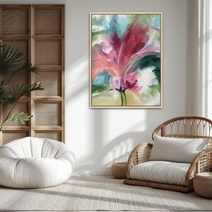 Pu&ograve; includere: Dipinto floreale astratto in cornice dorata su parete bianca. L'opera presenta un grande fiore stilizzato con sfumature di rosa, rosso e verde. Un pouf bianco e una sedia in vimini con cuscino sono nella stanza.