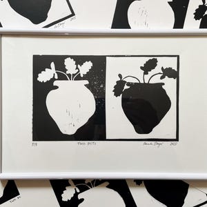 Könnte beinhalten: Ein Schwarz-Weiß-Linolschnitt von zwei Töpfen mit Pflanzen. Der Druck ist gerahmt und mit "Two Pots" betitelt, sowie mit dem Namen des Künstlers und dem Jahr 2015.