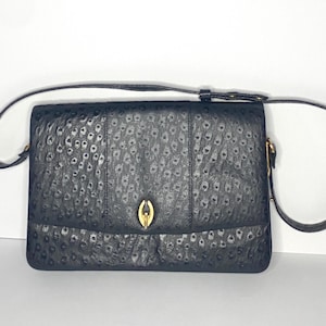 May include: A black ostrich leather shoulder bag with a gold clasp and a gold chain strap.