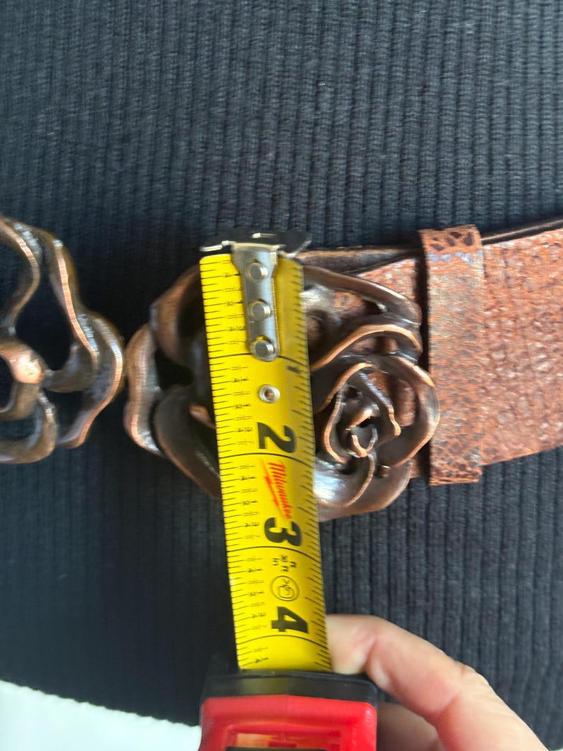 Wide dark brown leather belt with a large, sculptural double-rose copper buckle