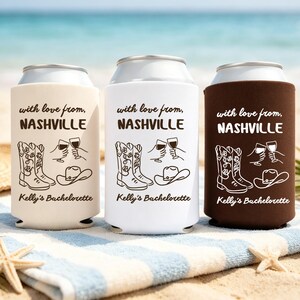 Puede incluir: Tres enfriadores de latas de espuma en beige, blanco y marrón oscuro. Cada uno presenta el texto "with love from, NASHVILLE" y "Kelly's Bachelorette" con un gráfico de botas vaqueras, un sombrero vaquero y dos manos brindando con copas.