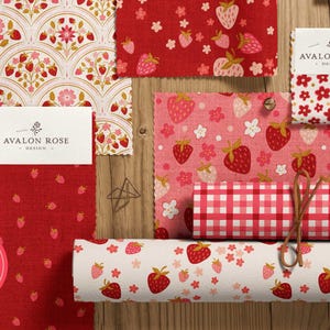 May include: A collection of fabric swatches with strawberry patterns in red, pink, and white. Designs include strawberries, flowers, and gingham. The Avalon Rose Design logo is visible on several tags. A circular sticker reads "Strawberry Delicious."