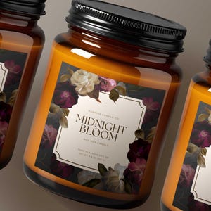 May include: Three glass jar candles with black lids. The labels read "Midnight Bloom" with floral illustrations in shades of purple, white, and green. The candles are filled with a golden-orange wax.