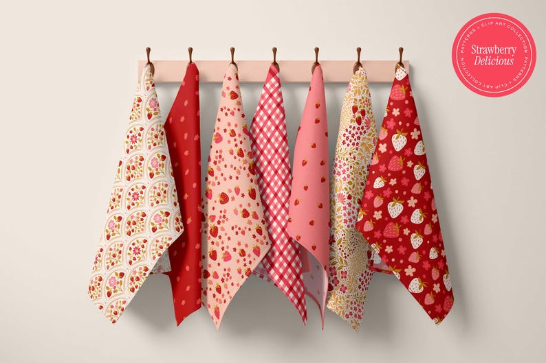 May include: A collection of six strawberry-themed kitchen towels hanging on a wooden rack. The towels feature various patterns, including strawberries, floral designs, and gingham checks, in shades of red, pink, and white. A circular sticker reads "Strawberry Delicious."