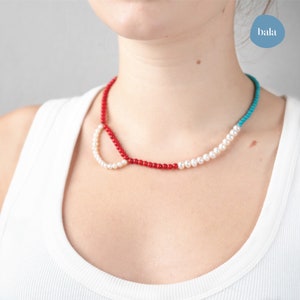Necklace made with multiple pieces of stone: freshwater pearls, red howlite, blue howlite.