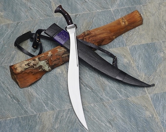 May include: A curved, silver-colored sword with a black leather scabbard and a wooden handle. The sword is resting on a wooden log with a leather strap.