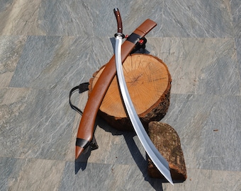 May include: A curved, silver-coloured sword with a brown leather scabbard. The sword is resting on a wooden log and a piece of wood.