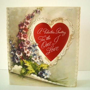 May include: Vintage Valentine's Day card with a red heart and floral bouquet. The heart contains the text "A Valentine Greeting For the One I Love". The card has a scalloped edge and a light gray background. The year 1949 is written in the upper right corner.