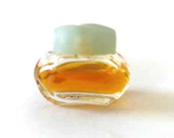 May include: A small, clear glass bottle with a light blue lid. The bottle is filled with a golden liquid.