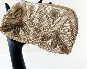 May include: A white beaded clutch purse with gold accents and a floral design. The purse is on a black display stand.