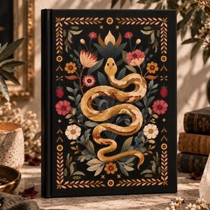 Puede incluir: Un libro de tapa dura negra con una ilustración central de una serpiente de color canela enroscada entre flores coloridas y follaje verde. La cubierta está enmarcada por un borde decorativo con patrones geométricos y motivos florales en tonos dorados.