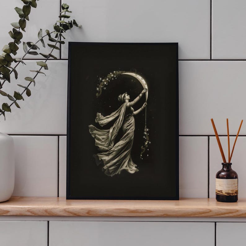 May include: Black framed art print featuring a woman reaching for a crescent moon adorned with stars. The woman is draped in flowing fabric, set against a dark background. The artwork evokes a celestial and ethereal theme.