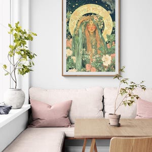 May include: A framed art print featuring a woman with long red hair, adorned with a floral crown and surrounded by flowers. The artwork has a vintage aesthetic with a golden halo and a soft color palette of greens, pinks, and creams.